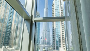 A view through a window of a high-rise building with a prominent skyscraper in the background. - 2BR w Burj Khalifa View near Dubai Mall (Dubai)