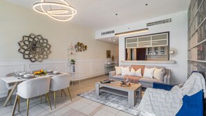 A modern living room with a dining area, featuring a sofa, coffee table, and a dining table with chairs. - 2BR w Burj Khalifa View near Dubai Mall (Dubai)