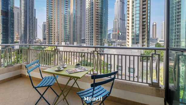 A balcony with a table and chairs, overlooking a cityscape with tall buildings. - 2BR w Burj Khalifa View near Dubai Mall (Dubai)