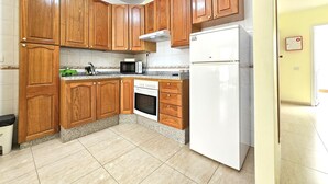 Une cuisine avec des meubles de rangement en bois, un four à micro-ondes, un four traditionnel et un réfrigérateur.