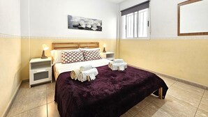 Une chambre à coucher avec un lit, deux tables de chevet, une fenêtre avec des stores, un tableau accroché au mur et un mur uni.