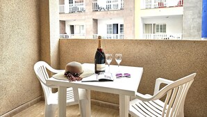 Un balcon avec une table dressée pour deux personnes, agrémentée d’une bouteille de champagne Moët & Chandon, de deux verres à vin, d’un chapeau de paille et d’une paire de lunettes de soleil.