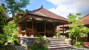 A traditional wooden pavilion with a tiled roof, surrounded by lush greenery and a decorative stone pathway. - Puri Karang Residence (Tembuku)