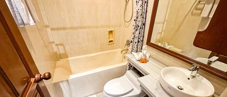 A bathroom with a bathtub, toilet, sink, and a mirror.