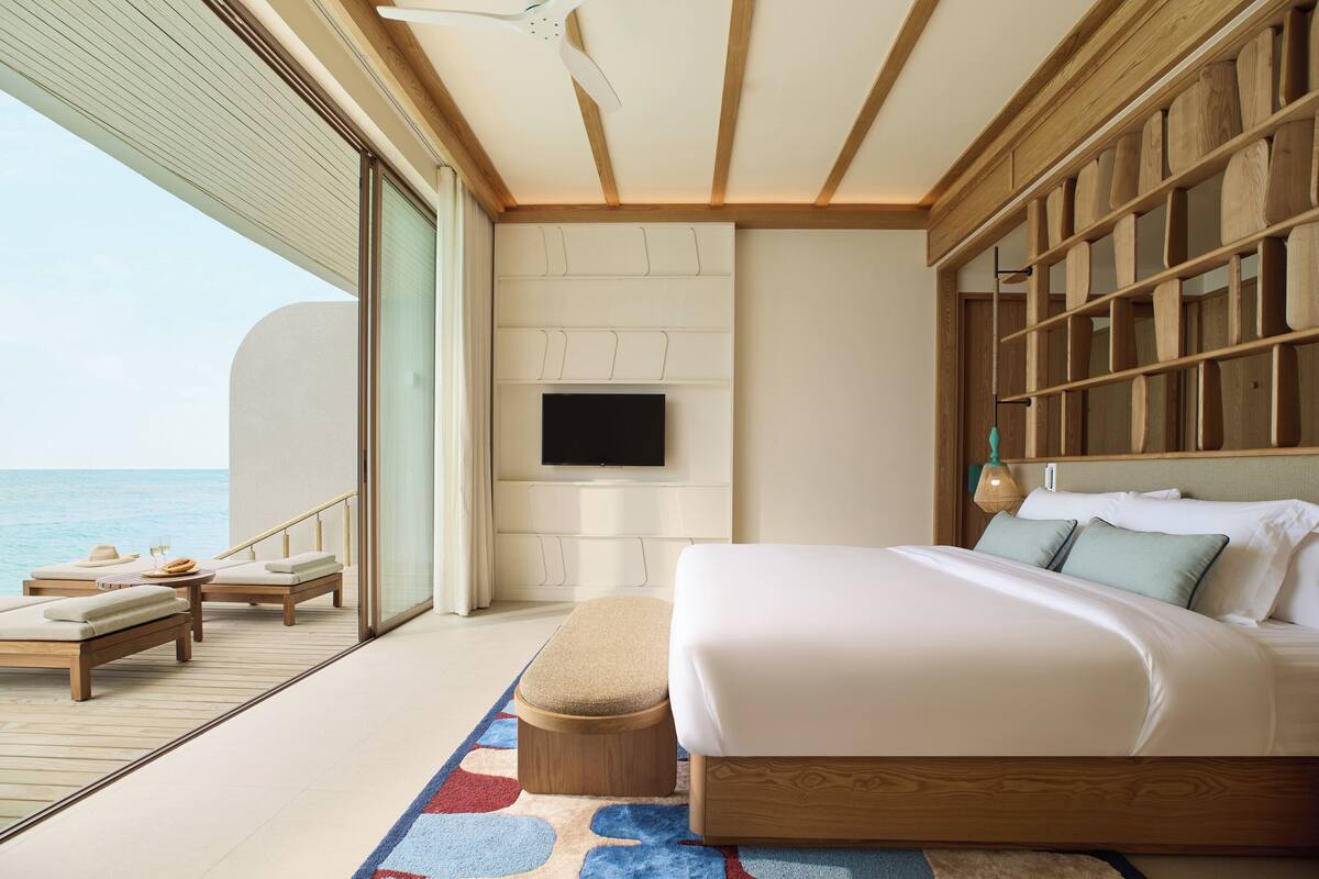 Ein Schlafzimmer mit einem großen Bett, einem an der Wand befestigten Fernseher und Meerblick.