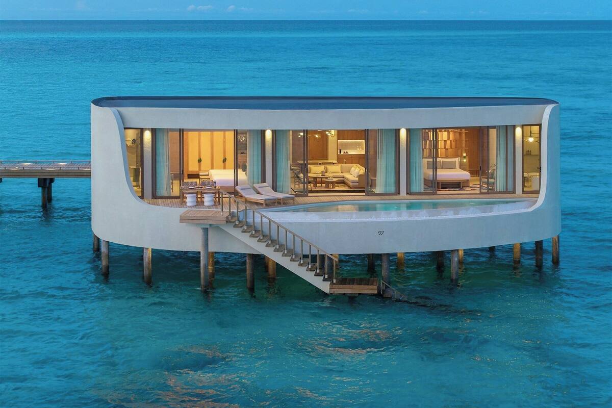 Un hôtel moderne, construit sur pilotis au-dessus de l’eau, doté d’une piscine, d’espaces de détente et d’un escalier menant à l’intérieur.