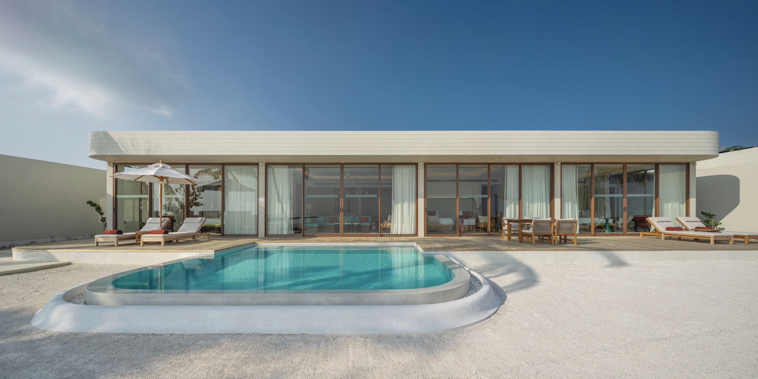 A modern house with a swimming pool, large windows, and outdoor seating.