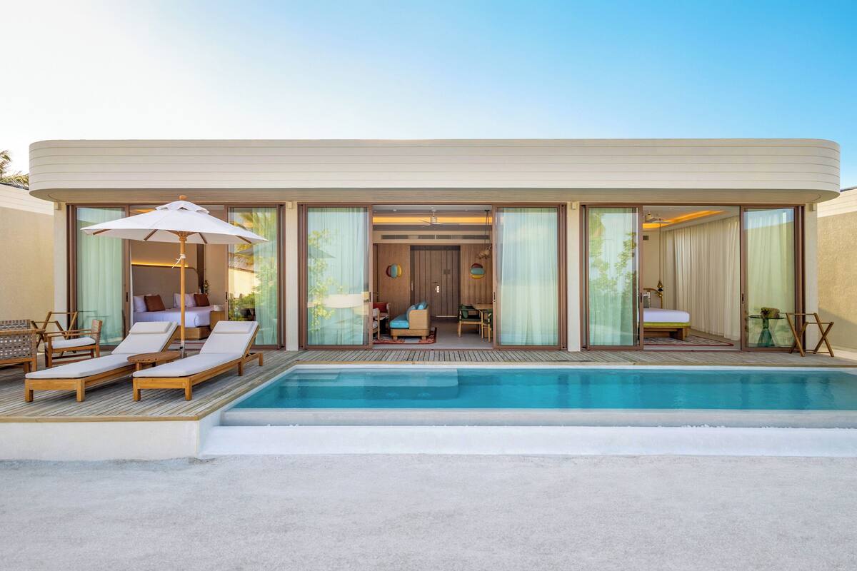 Un hôtel moderne doté d’une piscine, de chaises longues et d’un intérieur bien éclairé.