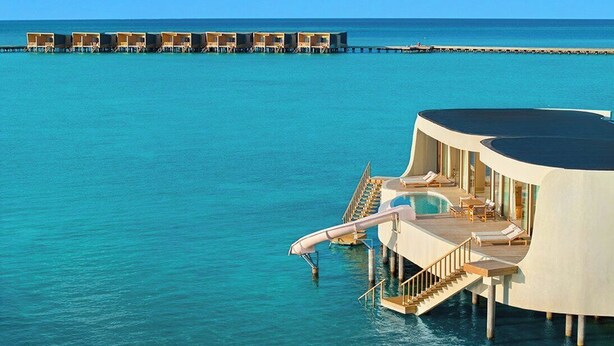 An overwater resort with a pool, lounge chairs, and a view of the ocean. - Centara Grand Lagoon Maldives (Kodhipparu Falhu)