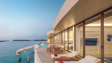 Un moderno resort con zona de piscina, sillones reclinables y vistas al océano.