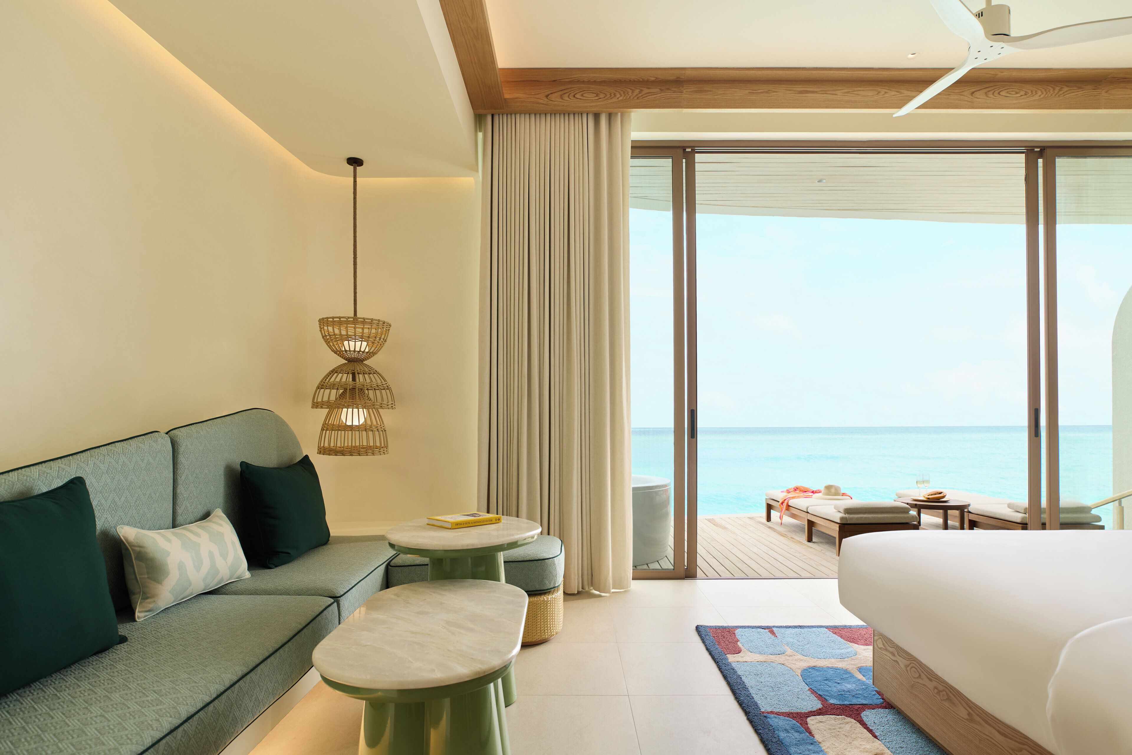 Une chambre d’hôtel avec un canapé, un lit, une petite table et une vue sur l’océan.