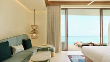 Une chambre d’hôtel avec un canapé, un lit, une petite table et une vue sur l’océan.