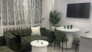 Un salon moderne avec un canapé vert, une table basse blanche et une table à manger ronde entourée de chaises.