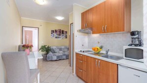 A compact kitchen with wooden cabinets, a white countertop, and a microwave.