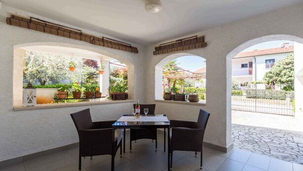 A patio area with a table and chairs, potted plants, and a view of the outside.