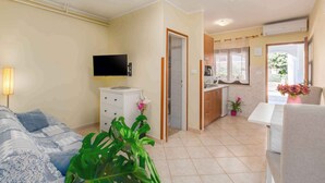 A compact living space with a bed, a TV, a kitchenette, and a dining area.