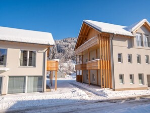 Un bâtiment moderne à deux étages, doté d’un balcon et d’un porche couvert, entouré de neige.