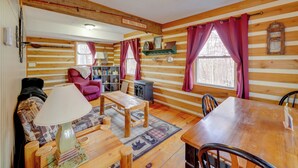 L’intérieur d’un chalet chaleureux, avec une table à manger en bois, un canapé, une lampe et une bibliothèque.