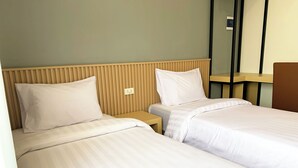 Una habitación de hotel con dos camas individuales, cabeceros de madera y una mesita de noche pequeña.