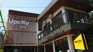 Un hotel con fachada moderna, un restaurante visible y un letrero de entrada.