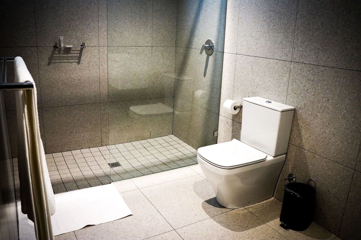 Une salle de bain équipée de toilettes, d’une douche et d’un sèche-mains.