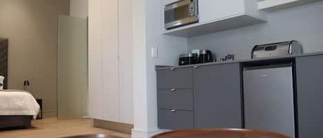 Una habitación de hotel moderna con una cama, una kitchenette y dos mesas de madera.