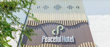 Un edificio con un letrero que dice "Peaceful Hotel" y una fachada decorativa con listones verticales.