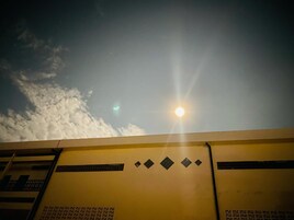 Un edificio con fachada amarilla y cielo despejado con nubes.