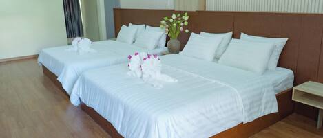 A hotel room with two beds, a wooden headboard, a vase with flowers, and a wooden nightstand.