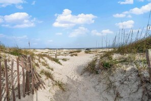 A sandy beach path with wooden fencing and sparse vegetation. - Ohana Bliss l 2 Pools l Walk to Beach (St. Augustine Beach)