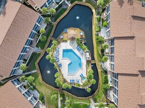 An aerial view of a resort with a central swimming pool, surrounded by lounge areas with umbrellas and sun loungers, and a small hot tub area. - Ohana Bliss l 2 Pools l Walk to Beach (St. Augustine Beach)