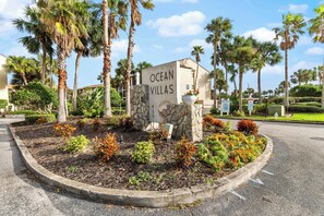 A sign for Ocean Villas with a stone base and a potted plant. - Ohana Bliss l 2 Pools l Walk to Beach (St. Augustine Beach)