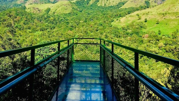 A bridge leading to a lush green valley with mountains in the background. - Green Mountain Resorts (Vythiri)