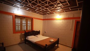 A bedroom with a wooden bed, a window with blinds, a brick wall, and a wooden ceiling. - Green Mountain Resorts (Vythiri)