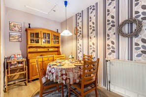 Un comedor con una mesa redonda, sillas, un armario de madera y una pared decorada con un adorno festivo.