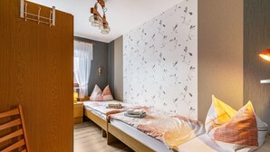 Une pièce comprenant un lit en bois, une chaise, une table de chevet et un luminaire fixé au mur.