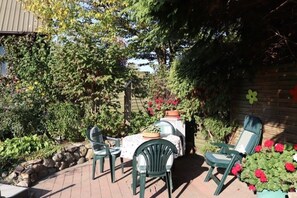 Un patio con mesa y sillas, rodeado de plantas y una valla de madera.