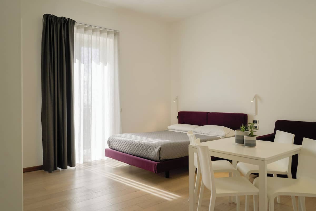 A modern hotel room with a bed, a desk, and a chair.