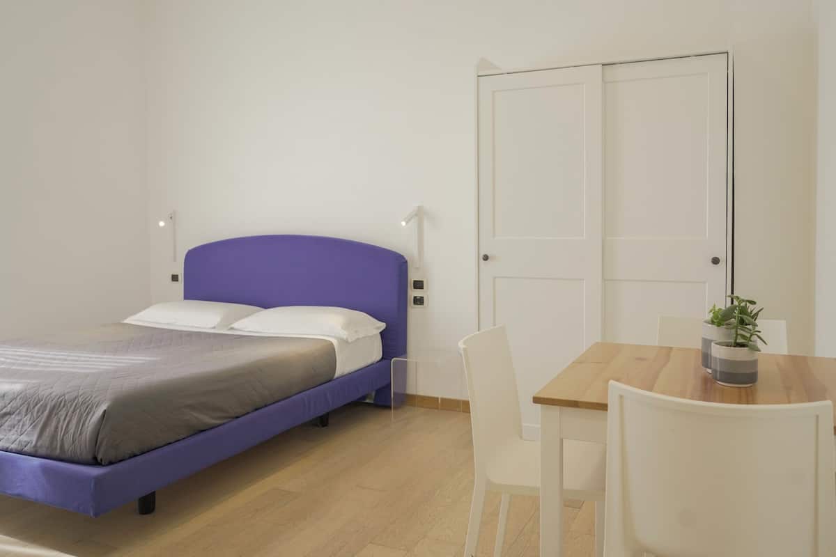 A bedroom with a bed, a desk, and a chair.