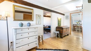 A room with a white dresser, a mirror, and a wooden chest of drawers. There is a small stool and a rug on the floor. - Holiday Apartment 'Reetdachhof Familie Dührsen' with Shared Terrace, Shared Garden and Wi-Fi (Norddeich)