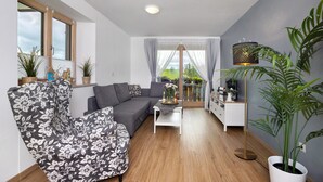 Ein modernes Wohnzimmer mit einem grauen Sofa, einem gemusterten Sessel, einem Couchtisch und einer Stehlampe.
