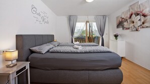 Ein modernes Schlafzimmer mit Bett, Nachttisch, Lampe und einem Bild an der Wand.
