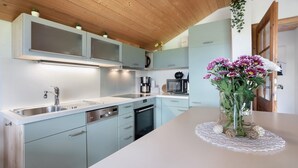 A modern kitchen with light blue cabinets, stainless steel appliances, and a wooden ceiling.