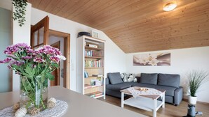 A living room with a sofa, a coffee table, a bookshelf, and a vase with flowers.
