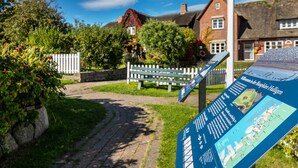A pathway leading to traditional houses with a signboard in the foreground. - Apartment 'Fewo- Nommensen' with Shared Garden and Wi-Fi (Oland)