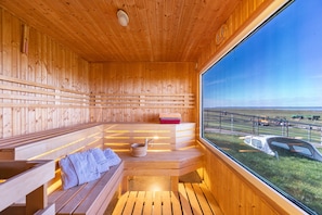Eine Holzsauna mit Bänken und einem großen Fenster mit Blick ins Freie.