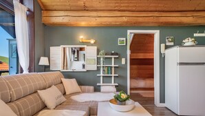 Ein gemütliches Wohnzimmer mit einer Couch, einem kleinen Tisch mit Pflanze, einem weißen Kühlschrank und einer Holzboden.