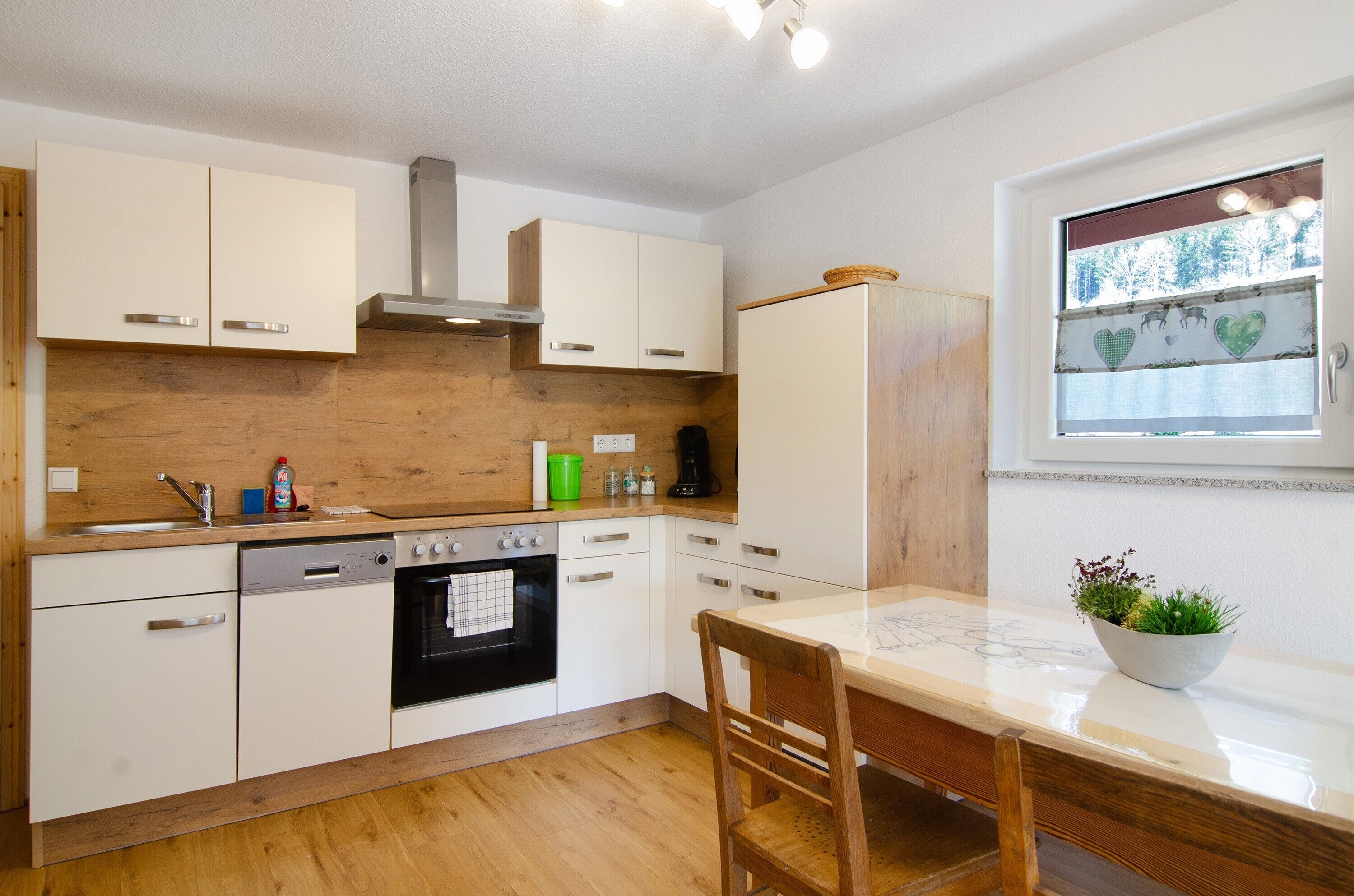 A modern kitchen with wooden cabinets, a built-in oven, and a dining area with a bench and a plant.