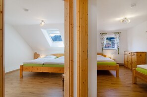 Une chambre avec un plafond en pente, un puits de lumière, un lit avec une literie verte, des meubles en bois et une vue par la fenêtre.