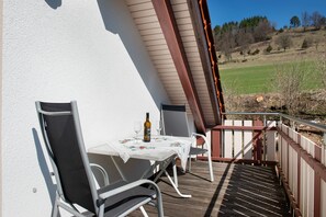 Un balcon avec une table, des chaises et une bouteille de vin.
